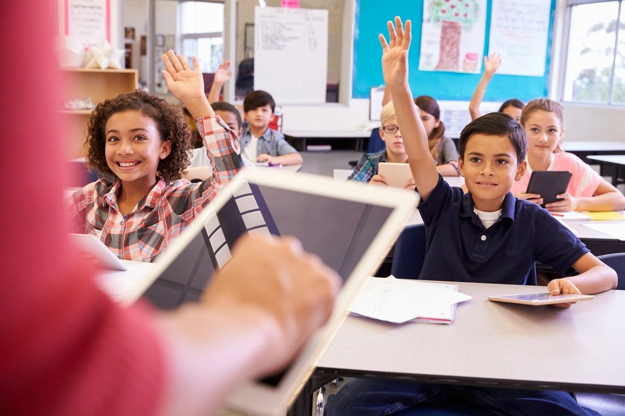 A group of students raising their hands in front of an instructor.