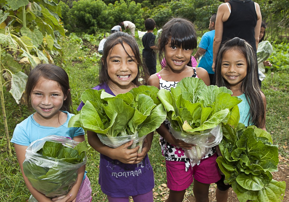 A group of young girls holding up plants.